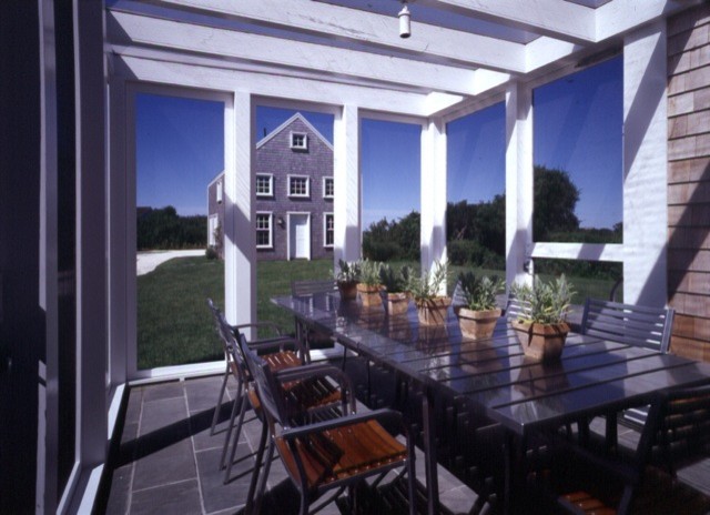 Expansive farmhouse back patio in DC Metro with natural stone paving and a pergola.