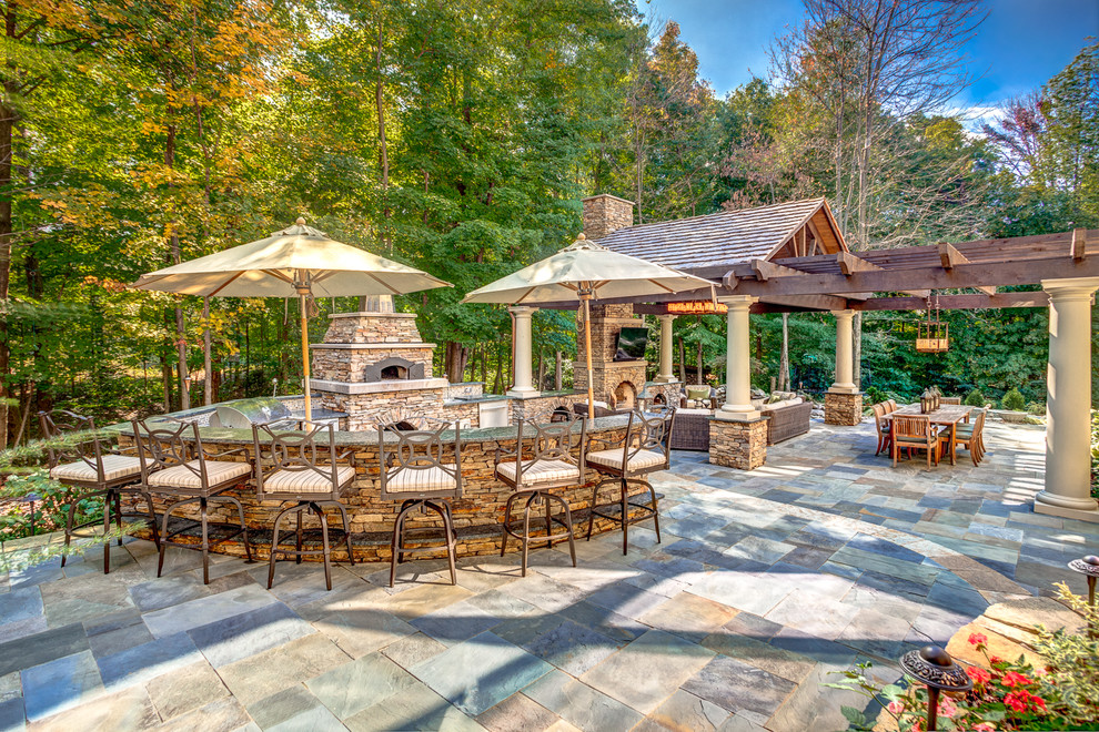 Inspiration pour une terrasse chalet avec des pavés en pierre naturelle, un foyer extérieur et une pergola.