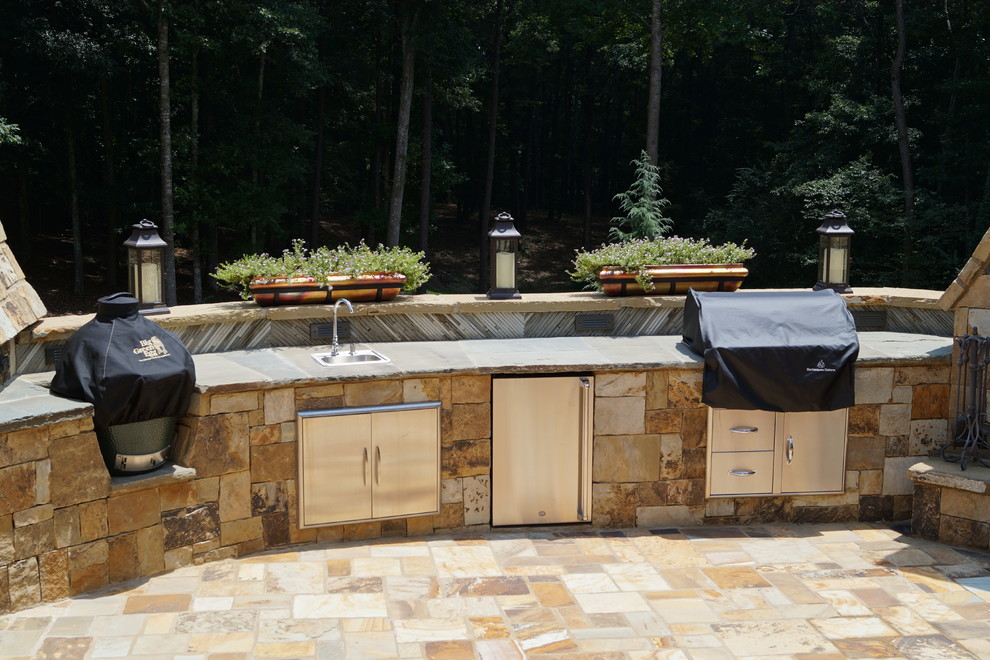 Cette image montre une très grande terrasse arrière chalet avec une cuisine d'été, des pavés en pierre naturelle et aucune couverture.