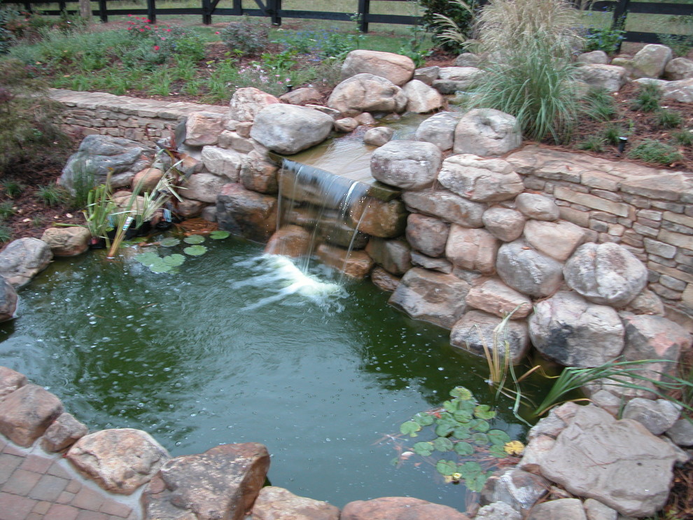Example of a large mountain style backyard concrete paver patio fountain design in Tampa with no cover