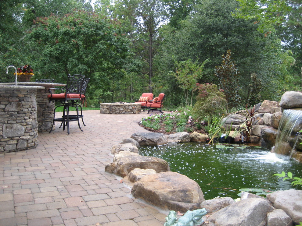 Inspiration for a large rustic backyard concrete paver patio fountain remodel in Tampa with no cover
