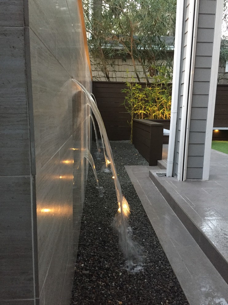 Kleiner, Unbedeckter Moderner Patio hinter dem Haus mit Wasserspiel und Granitsplitt in Jacksonville