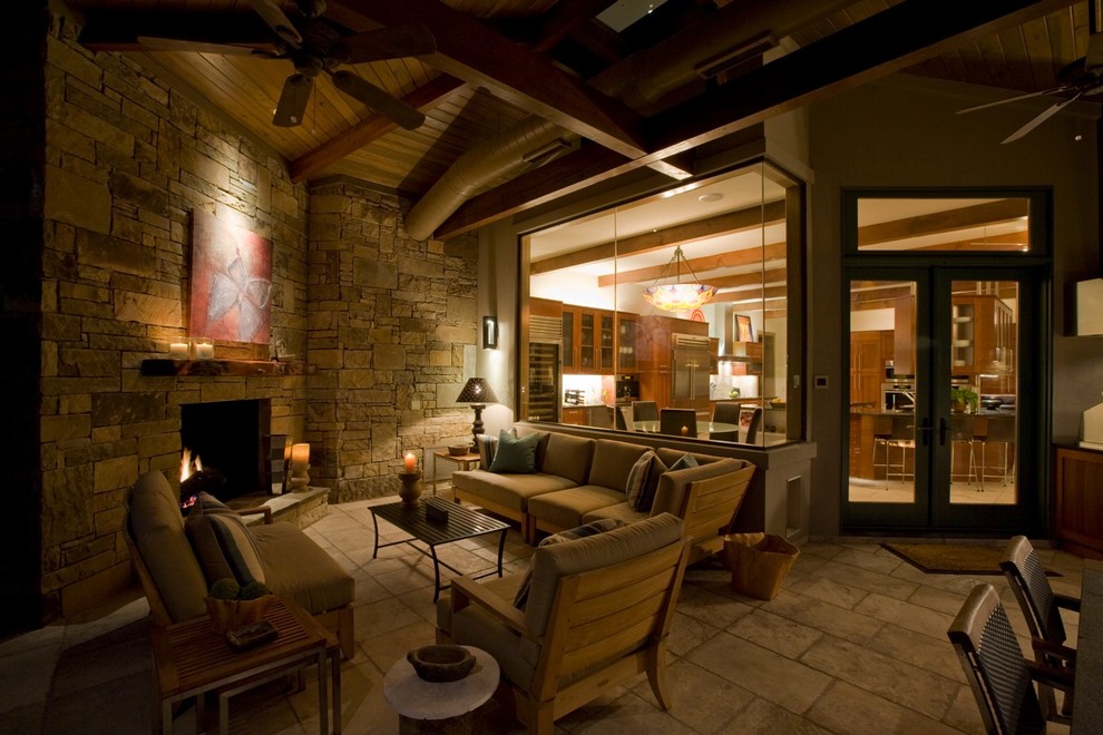 Photo of a large contemporary back patio in Austin with a fire feature, natural stone paving and a roof extension.