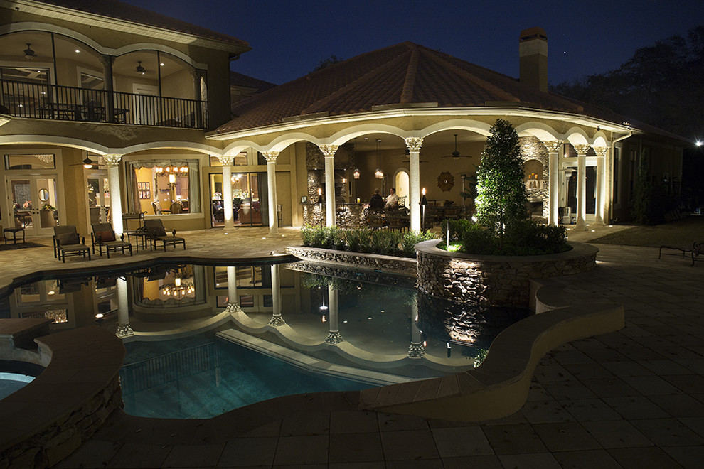 Example of a large tuscan backyard stone patio design in Tampa with a fire pit and a roof extension