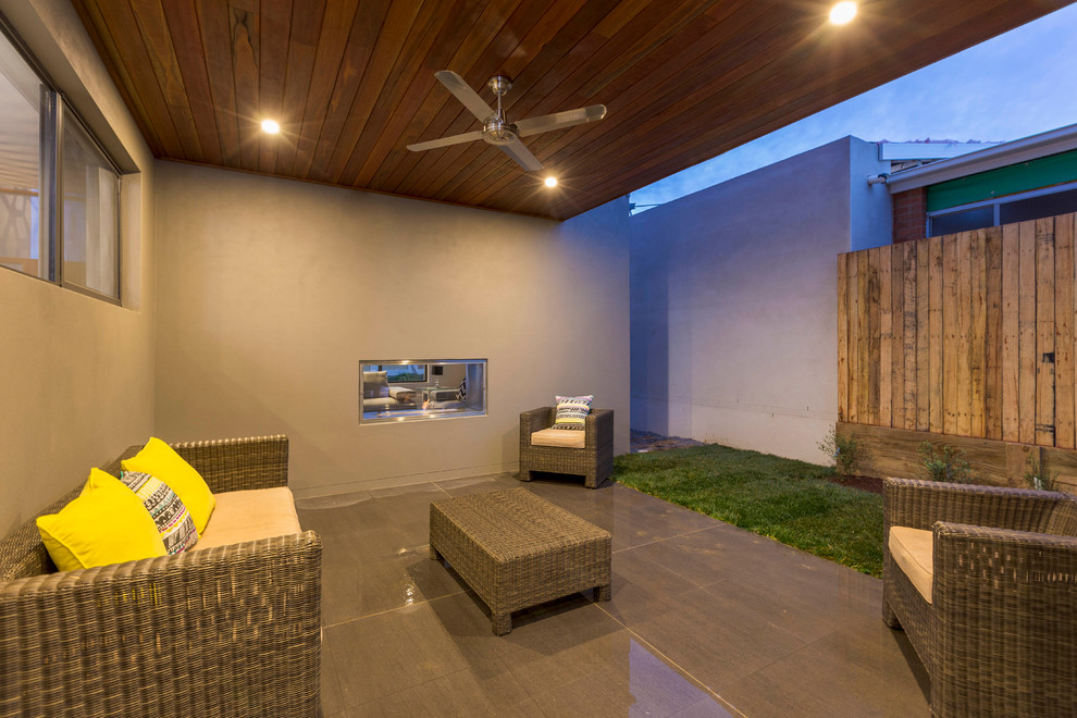 Cette photo montre une terrasse latérale tendance avec un foyer extérieur, du carrelage et une extension de toiture.