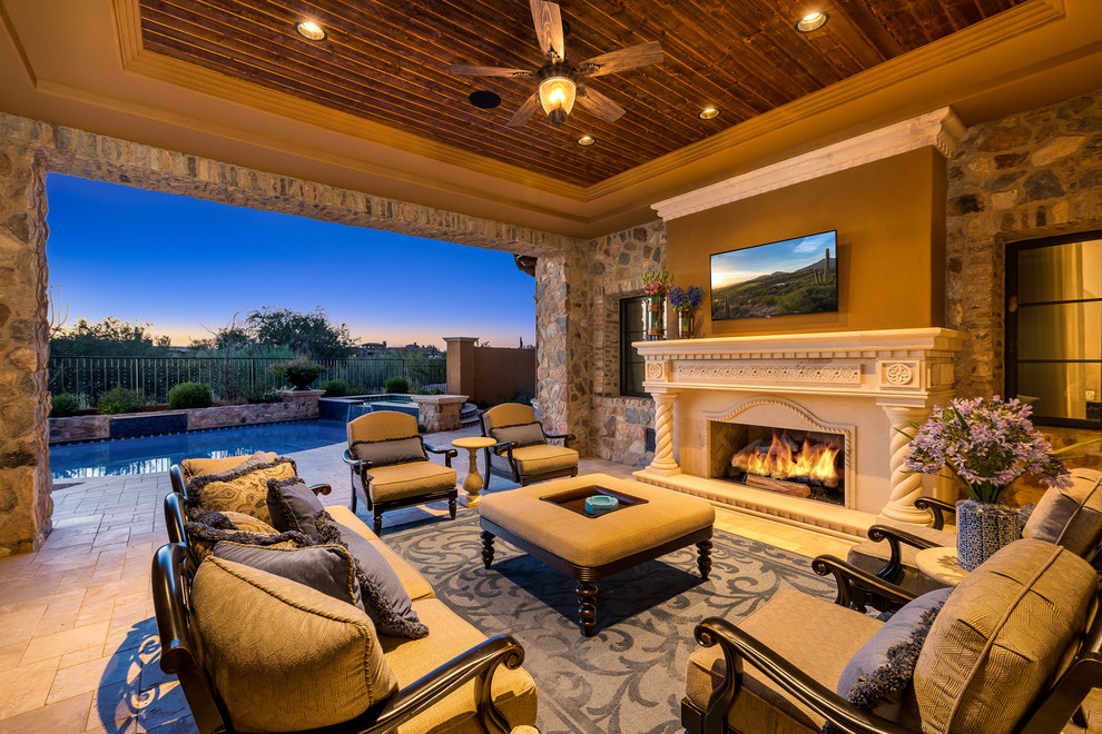 Photo of an expansive courtyard patio in Phoenix with a fire feature, natural stone paving and a roof extension.