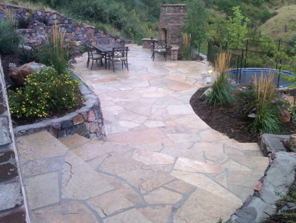 Large rustic back patio in Denver with natural stone paving and no cover.
