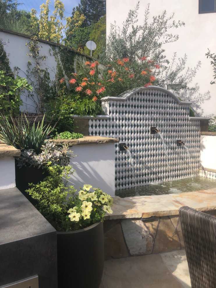 Cette image montre une grande terrasse minimaliste avec un point d'eau, une cour et des pavés en pierre naturelle.