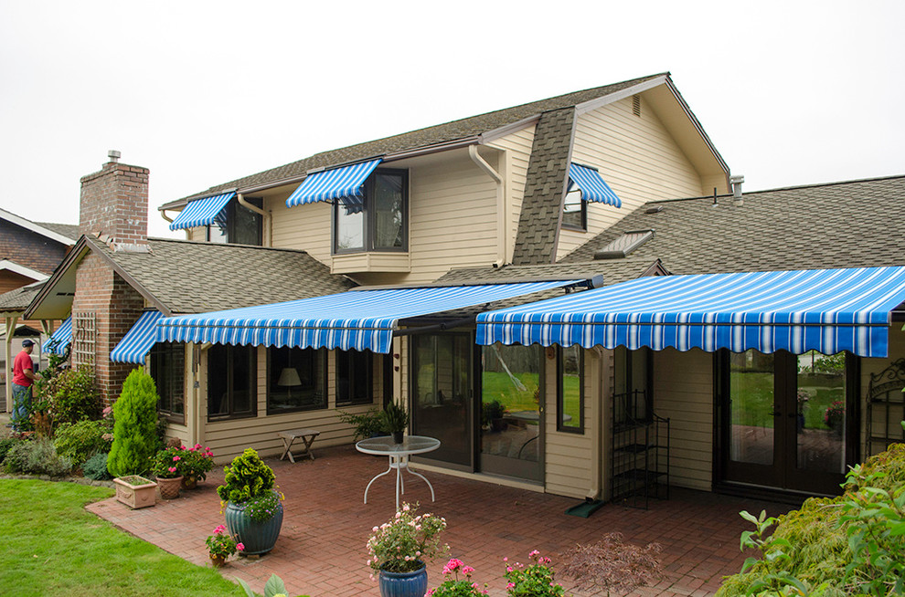 Immagine di un patio o portico tradizionale di medie dimensioni e dietro casa con pavimentazioni in mattoni, un parasole e un giardino in vaso