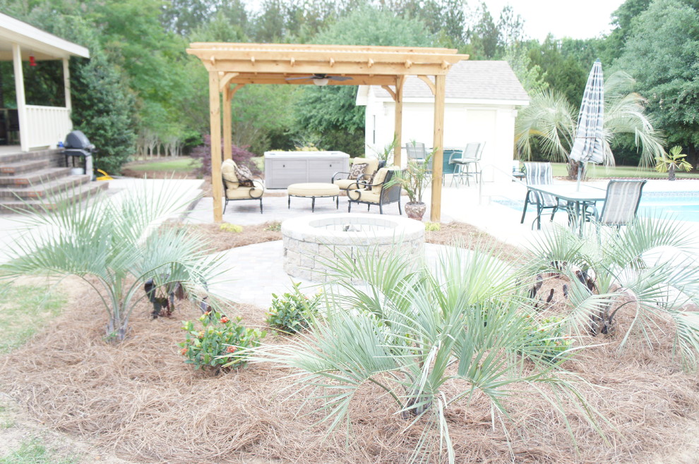 Inspiration for a mid-sized tropical backyard brick patio remodel in Atlanta with a fire pit and a pergola