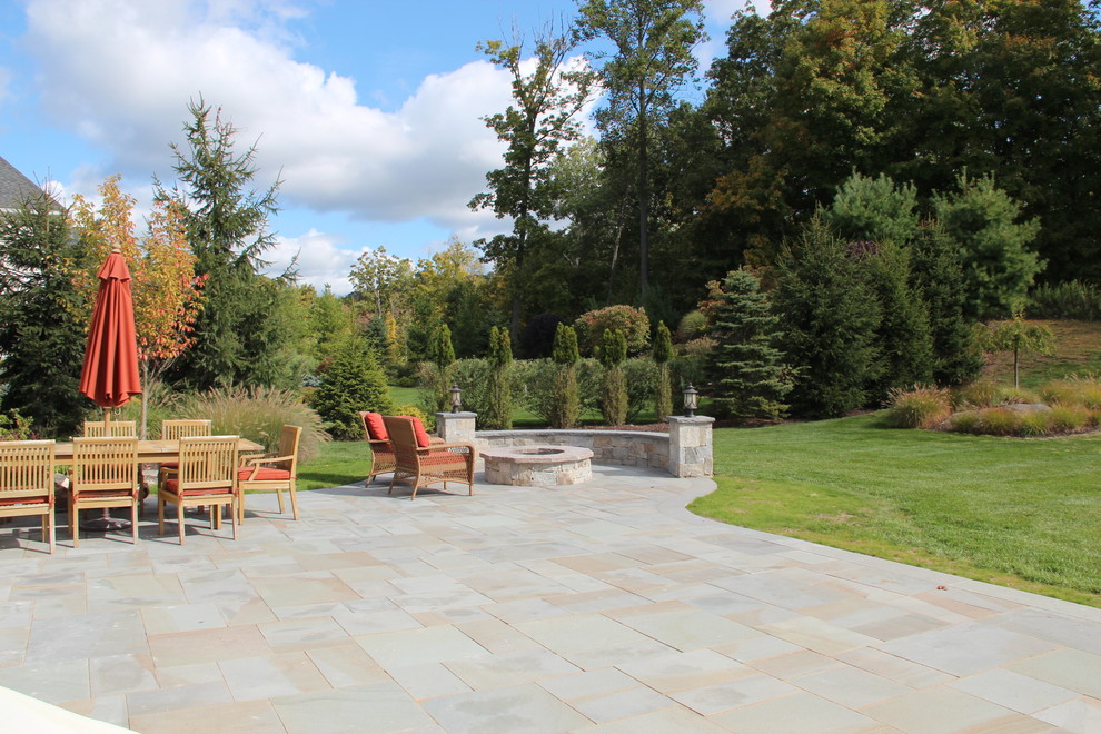 Photo of a large classic back patio in New York with a fire feature, tiled flooring and no cover.