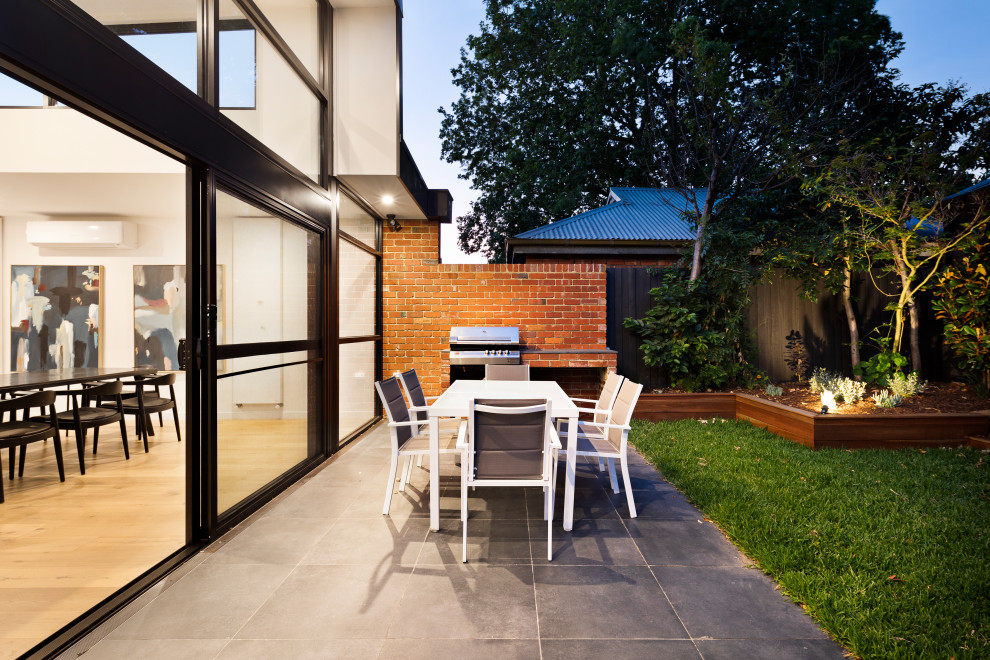 Ejemplo de patio minimalista de tamaño medio en patio trasero con cocina exterior, adoquines de piedra natural y pérgola
