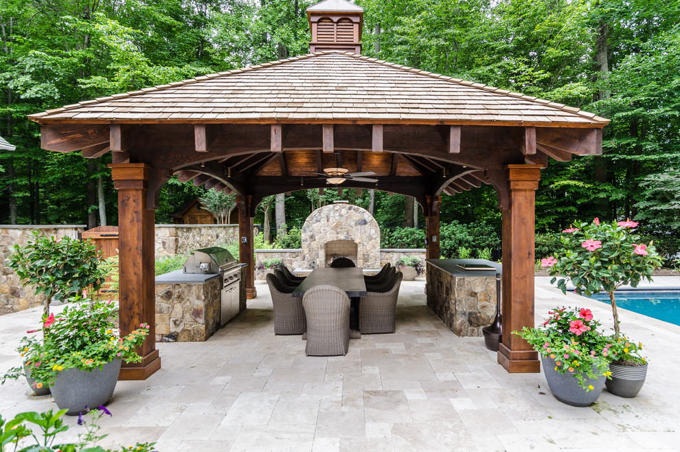 Cette image montre une grande terrasse arrière craftsman avec une cuisine d'été, des pavés en pierre naturelle et un gazebo ou pavillon.
