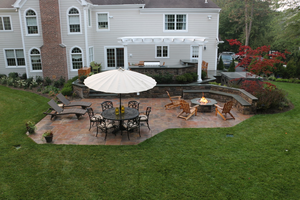 Idées déco pour une grande terrasse arrière classique avec une cuisine d'été, des pavés en pierre naturelle et une pergola.