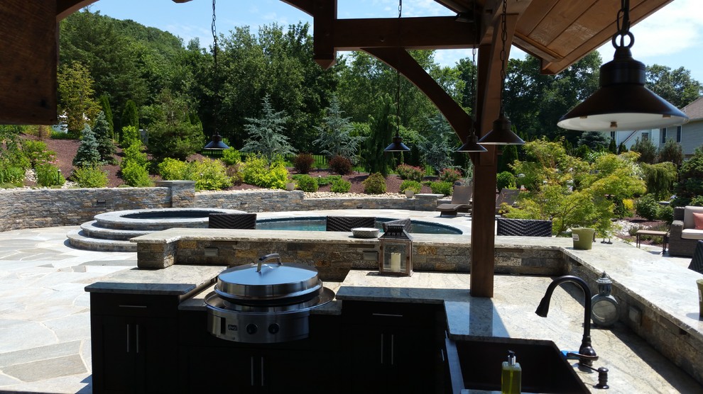 Inspiration for a large transitional backyard stone patio kitchen remodel in New York with a gazebo