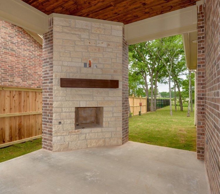 Idee per un patio o portico american style di medie dimensioni e dietro casa con un focolare, lastre di cemento e un tetto a sbalzo