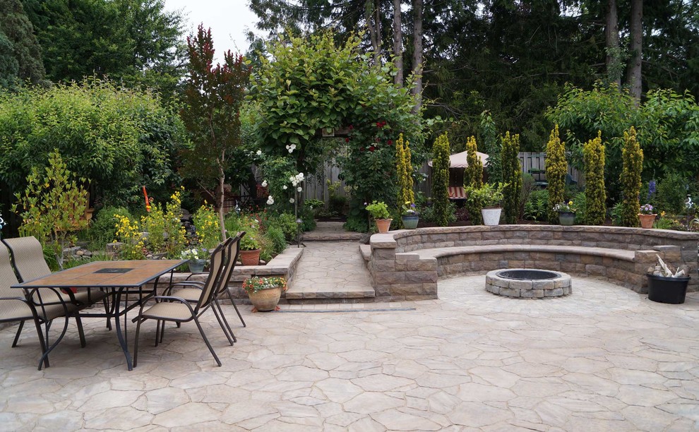 This is an example of a medium sized modern back patio in Portland with a fire feature and concrete paving.