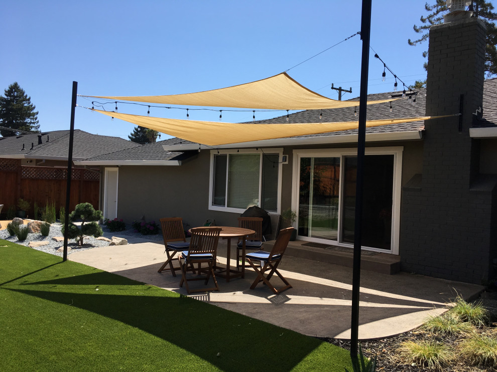 Immagine di un patio o portico design di medie dimensioni e dietro casa con lastre di cemento e un parasole