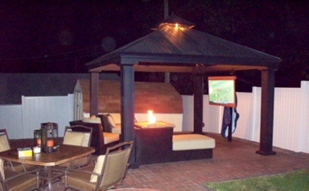 Foto di un ampio patio o portico moderno dietro casa con un focolare, pavimentazioni in mattoni e un gazebo o capanno
