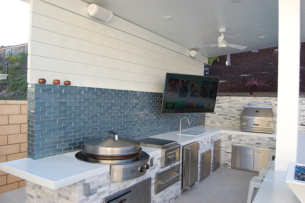 Cette photo montre une terrasse arrière tendance de taille moyenne avec une cuisine d'été, du carrelage et une extension de toiture.