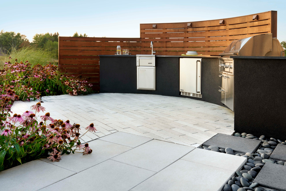 This is an example of an eclectic back patio in Toronto with an outdoor kitchen and concrete paving.