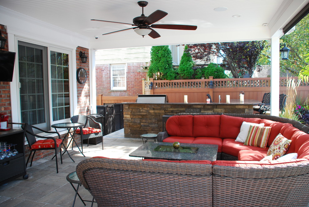 Cette image montre une grande terrasse arrière traditionnelle avec une cuisine d'été, des pavés en béton et une extension de toiture.