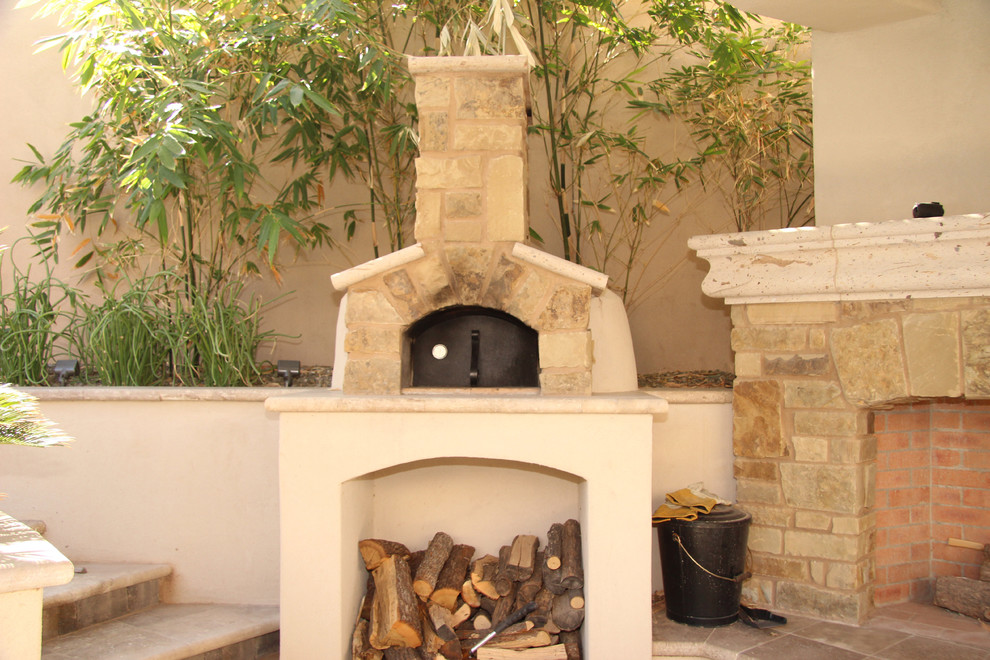 Idée de décoration pour une terrasse arrière méditerranéenne de taille moyenne avec des pavés en pierre naturelle et un gazebo ou pavillon.