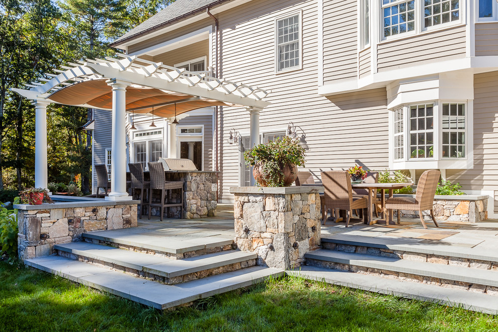 Große Klassische Pergola hinter dem Haus mit Outdoor-Küche und Natursteinplatten in Boston