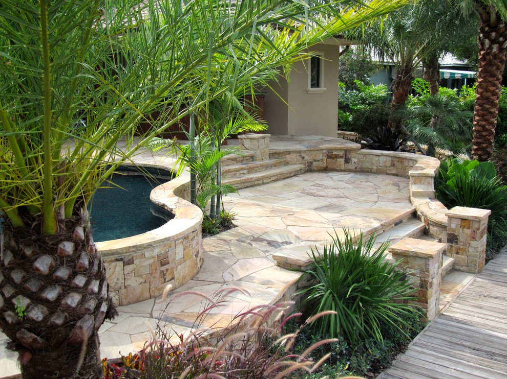 Imagen de patio exótico en patio trasero con adoquines de piedra natural