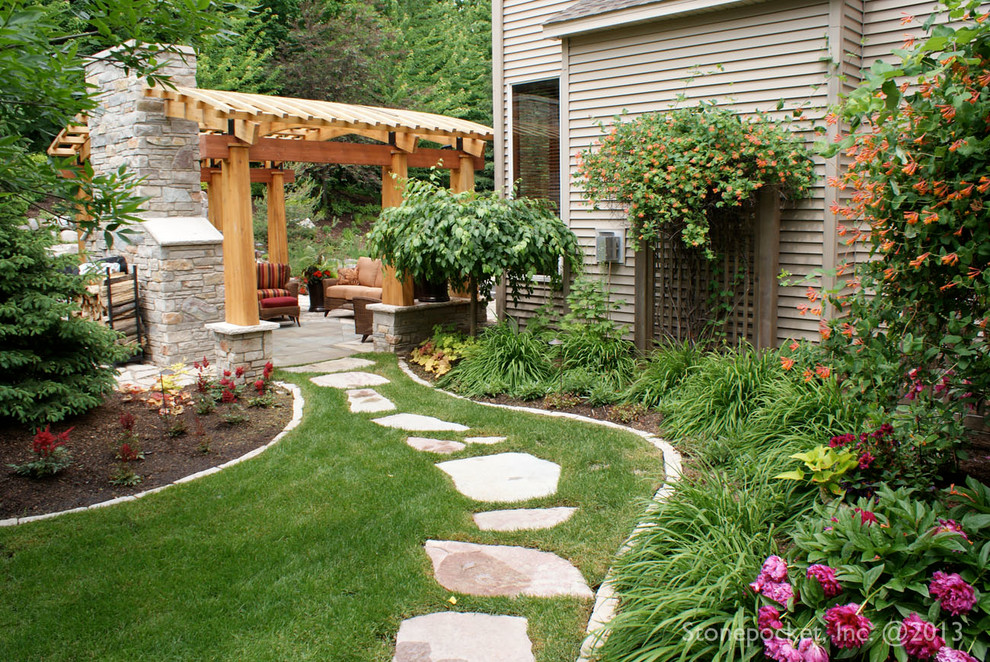 Diseño de patio clásico de tamaño medio en patio trasero con adoquines de piedra natural y pérgola