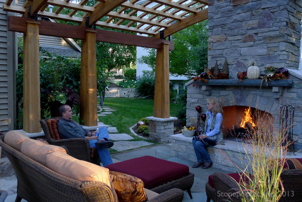 Example of a mid-sized classic backyard stone patio design in Minneapolis with a pergola