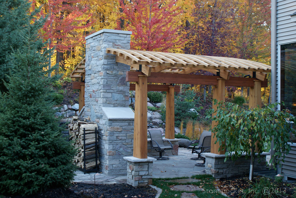 Exemple d'une terrasse arrière chic de taille moyenne avec un foyer extérieur, des pavés en pierre naturelle et une pergola.