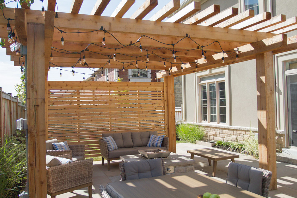 Example of a small trendy backyard stone patio design in Toronto with a fire pit and a pergola