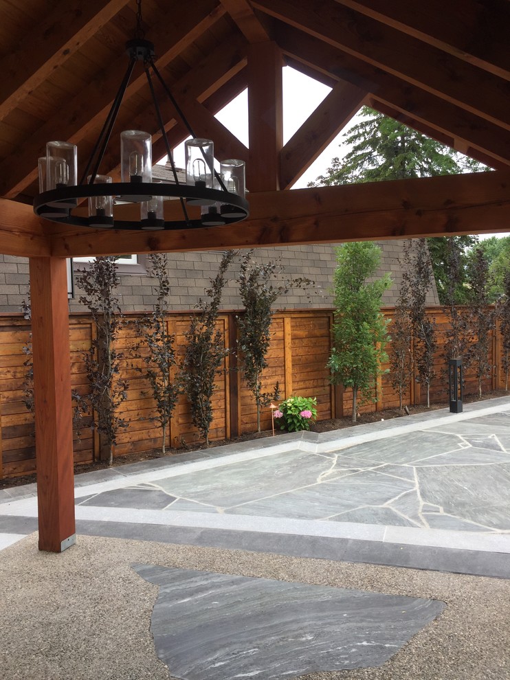 Cette image montre une grande terrasse arrière design avec des pavés en pierre naturelle et un gazebo ou pavillon.