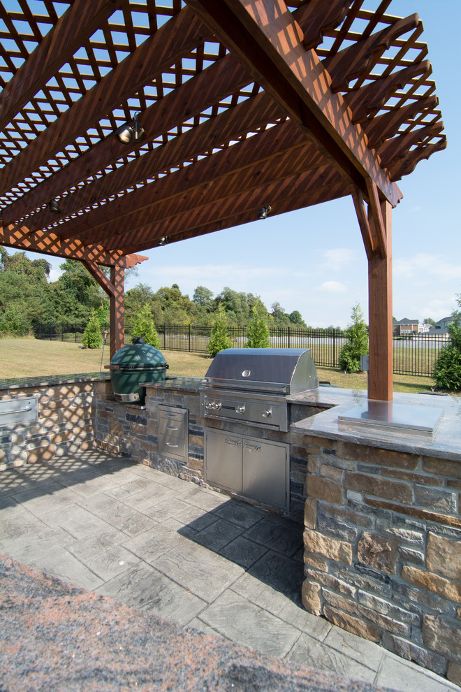 Cette photo montre une très grande terrasse arrière chic avec une cuisine d'été, du béton estampé et une pergola.