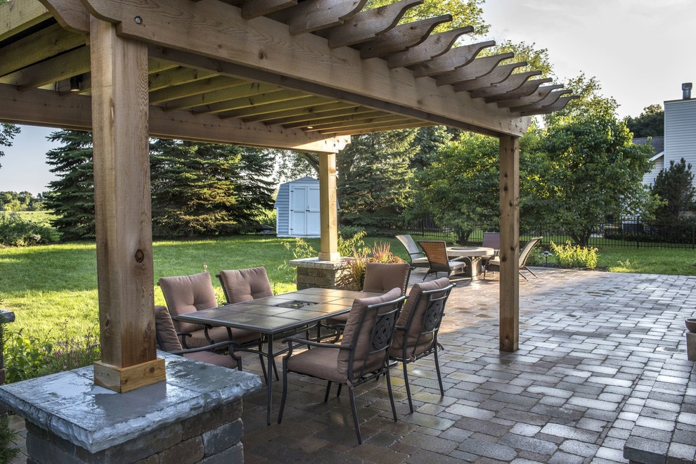 Foto di un patio o portico country dietro casa con un focolare, pavimentazioni in mattoni e una pergola