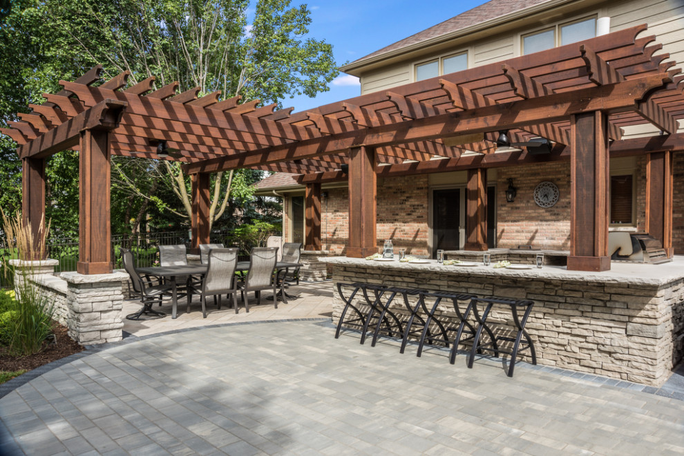 Inspiration pour une grande terrasse arrière traditionnelle avec une cuisine d'été, des pavés en brique et une pergola.