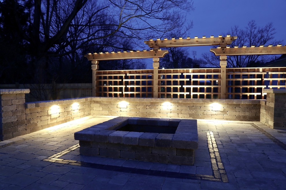 Example of a large classic backyard concrete paver patio design in Other with a fire pit and a pergola