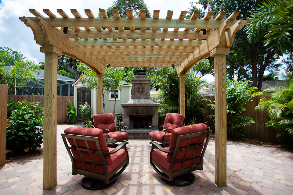 Ispirazione per un piccolo patio o portico tropicale dietro casa con un focolare, pavimentazioni in mattoni e un gazebo o capanno