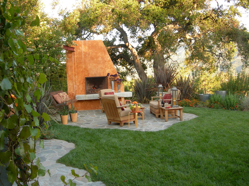 Ejemplo de patio actual sin cubierta con adoquines de piedra natural y chimenea