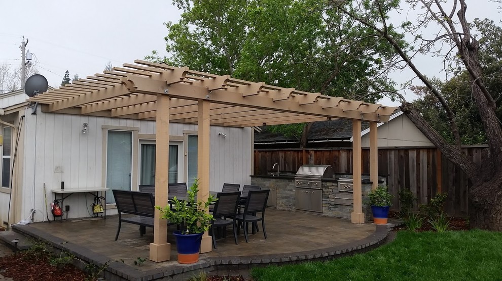 Exemple d'une terrasse arrière chic de taille moyenne avec une cuisine d'été, du carrelage et une pergola.