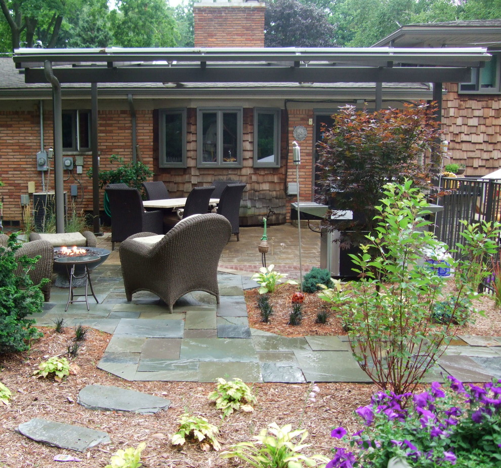 Diseño de patio rural grande en patio trasero con brasero, adoquines de piedra natural y pérgola