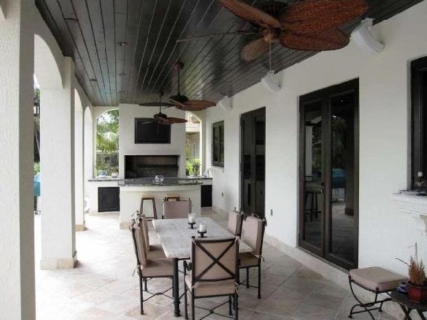 Inspiration for a large mediterranean backyard tile patio kitchen remodel in Miami with a roof extension