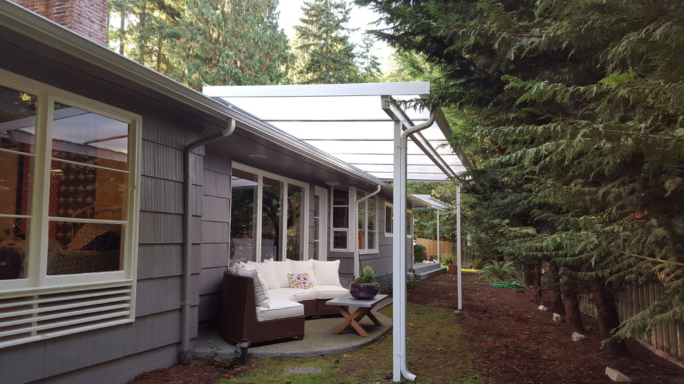 Example of a mid-sized mid-century modern backyard concrete paver patio design in Seattle with a pergola