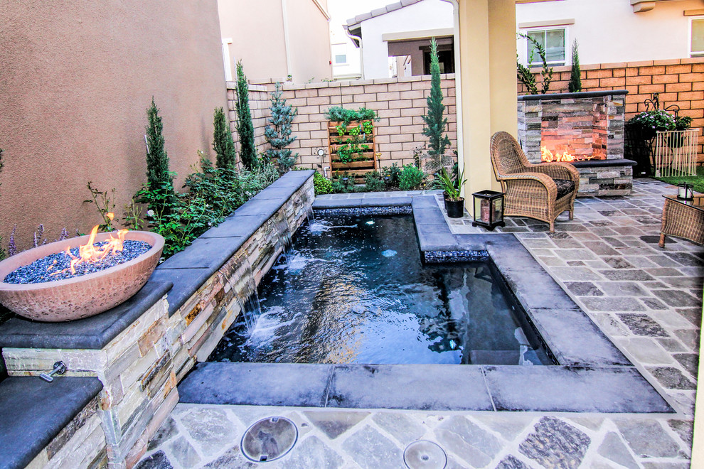 Example of a mid-sized classic backyard stone patio design in Orange County with a fireplace and a roof extension