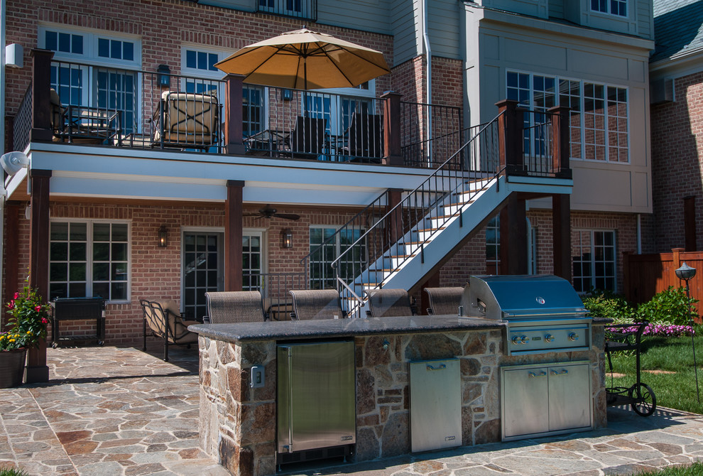 Immagine di un ampio patio o portico stile americano dietro casa con pavimentazioni in pietra naturale e un tetto a sbalzo