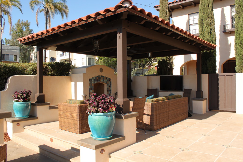 Idées déco pour une terrasse arrière méditerranéenne de taille moyenne avec un foyer extérieur, des pavés en béton et un gazebo ou pavillon.