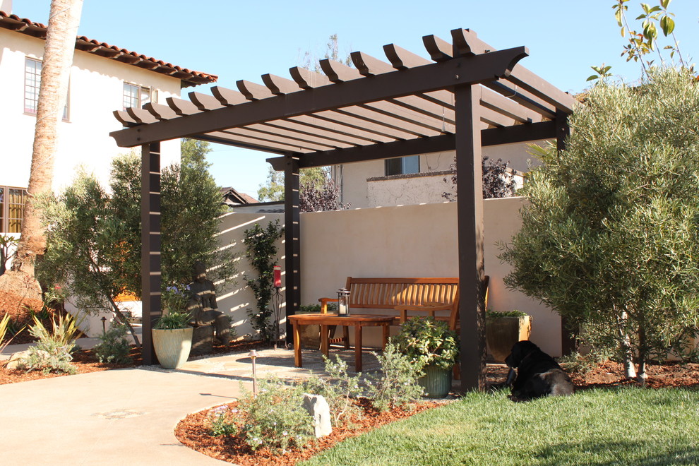 Modelo de patio mediterráneo de tamaño medio en patio trasero con jardín de macetas, adoquines de hormigón y pérgola