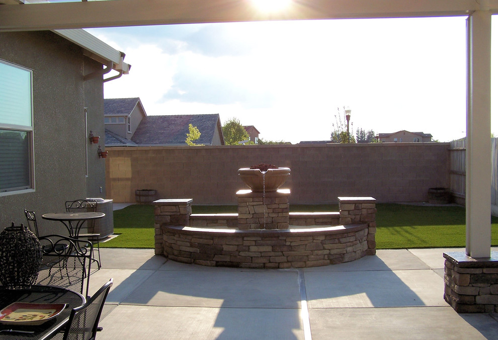 Foto di un grande patio o portico american style dietro casa con fontane, lastre di cemento e una pergola