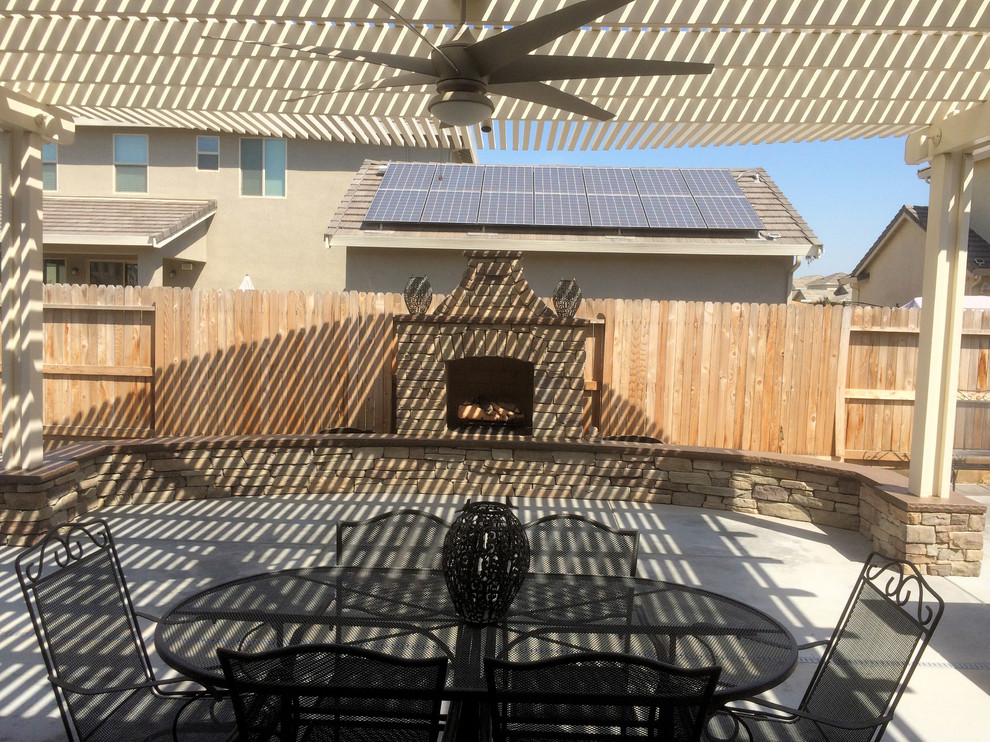 Immagine di un grande patio o portico stile americano dietro casa con un focolare, lastre di cemento e una pergola